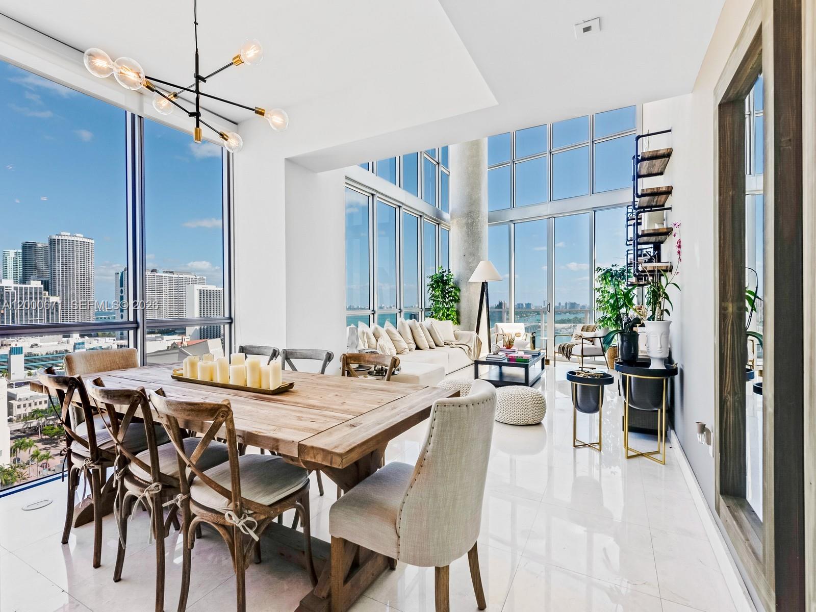 A modern dining and living area features floor-to-ceiling windows with expansive city and water views — 1100 Biscayne Blvd # 2105, Miami FL 33132, MIAMI, FL