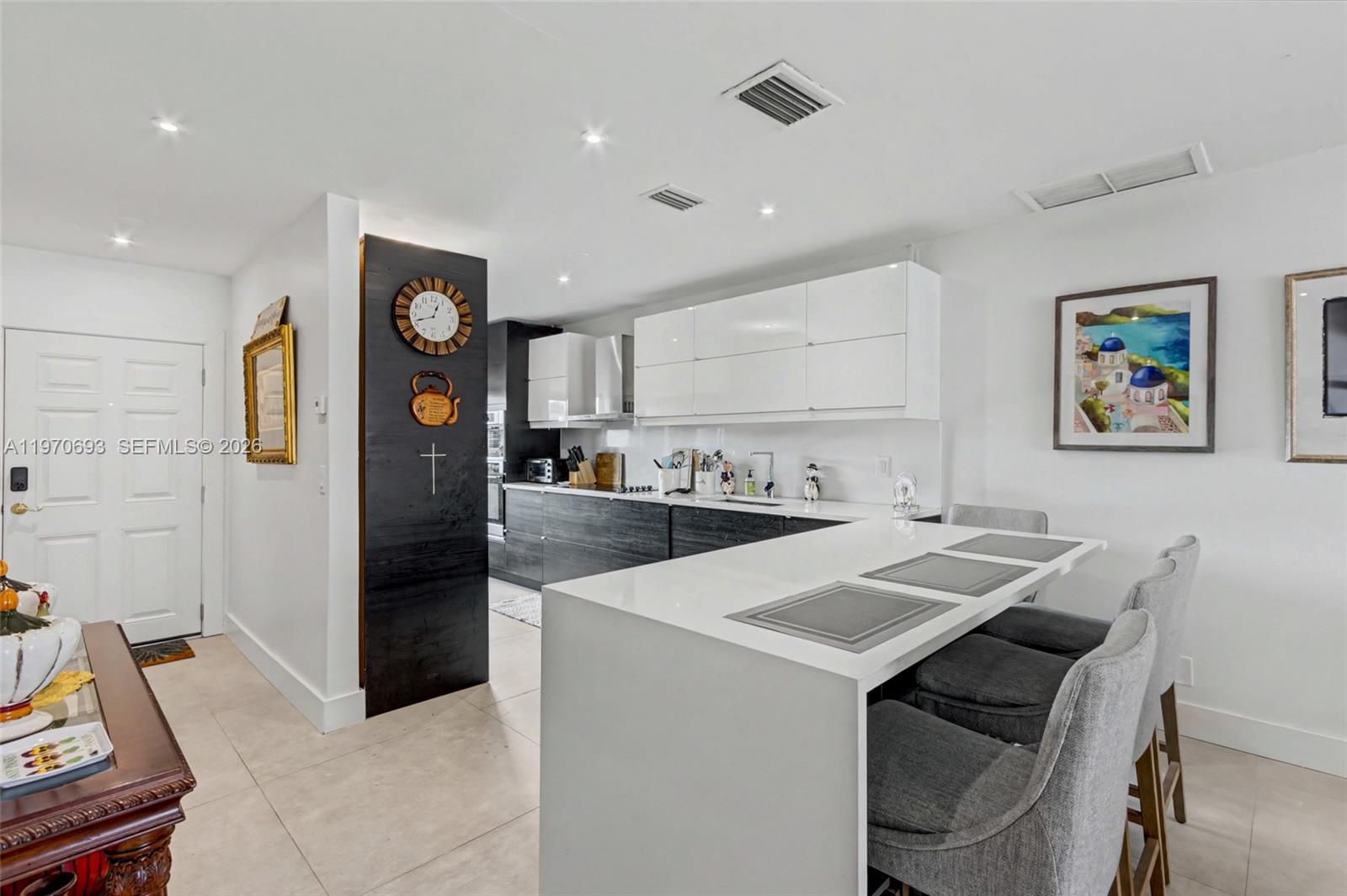A modern kitchen features white upper cabinets, dark lower cabinets, and a white island — 8953 Warwick Dr # 8953, Boca Raton FL 33433, BOCA RATON, FL
