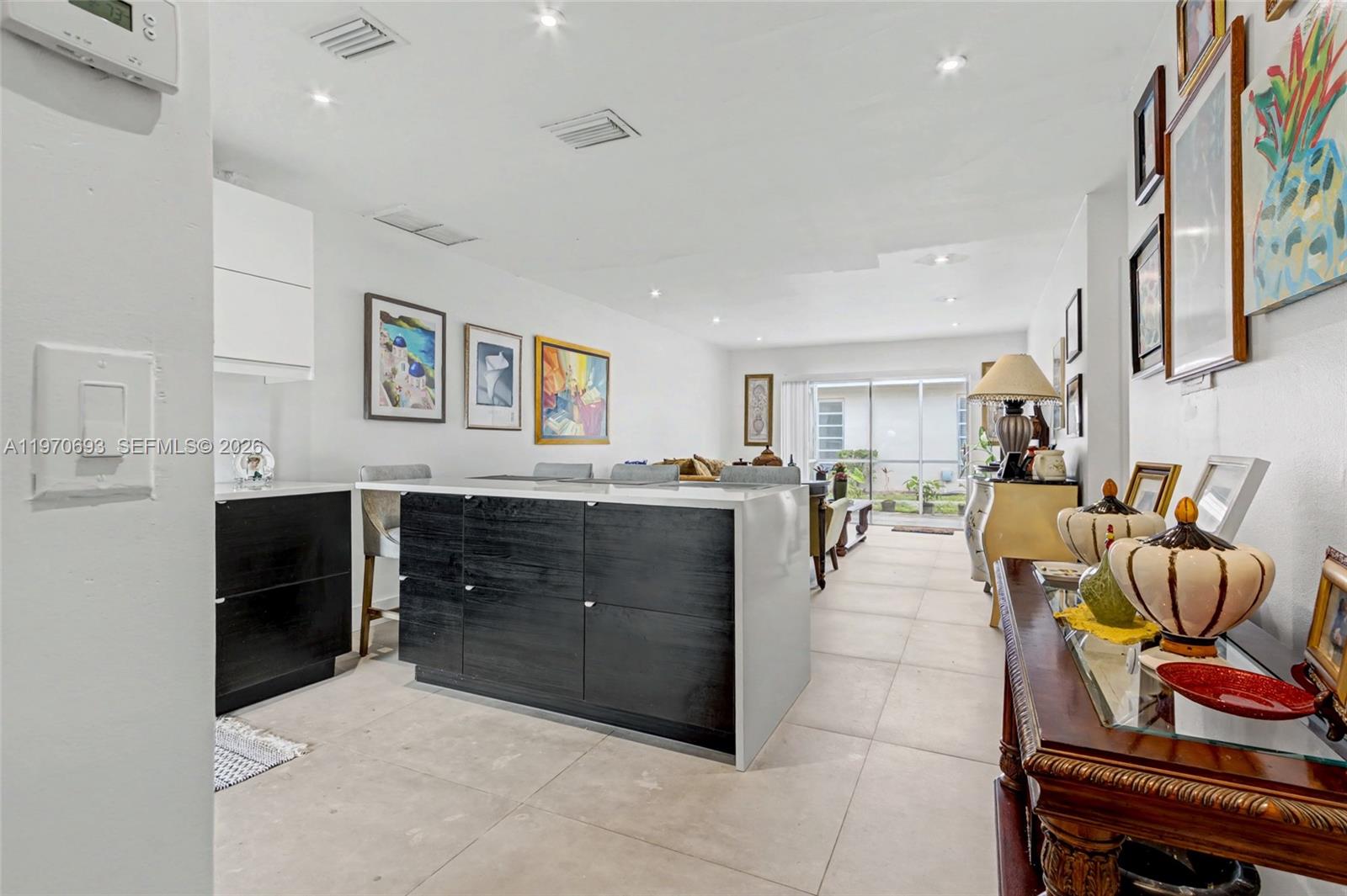 A kitchen island with dark cabinets and a white countertop sits in an open-plan living area — 8953 Warwick Dr # 8953, Boca Raton FL 33433, BOCA RATON, FL