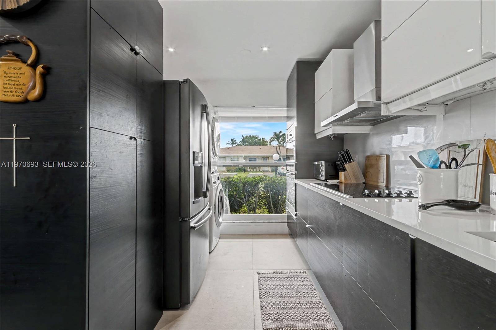 A galley kitchen features dark wood cabinetry, white countertops, stainless steel appliances, and a window view — 8953 Warwick Dr # 8953, Boca Raton FL 33433, BOCA RATON, FL