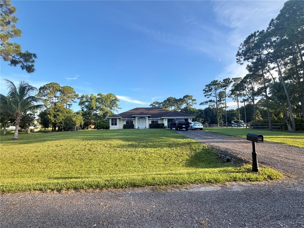 A single-story house with a gravel driveway sits on a large, grassy lot with trees — 17770 64TH PLACE N, LOXAHATCHEE, FL
