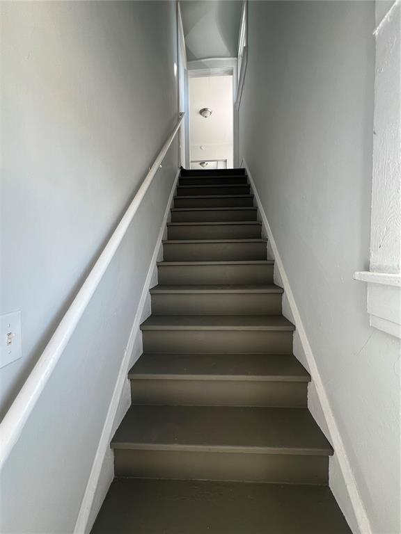 A straight staircase with dark painted steps leads upward between light gray walls — 209 TAYLOR AVENUE UNIT 2, DAYTONA BEACH, FL