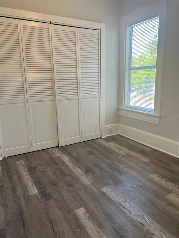 A room with white louvered closet doors, a window with blinds, and wood-look flooring — 209 TAYLOR AVENUE UNIT 2, DAYTONA BEACH, FL