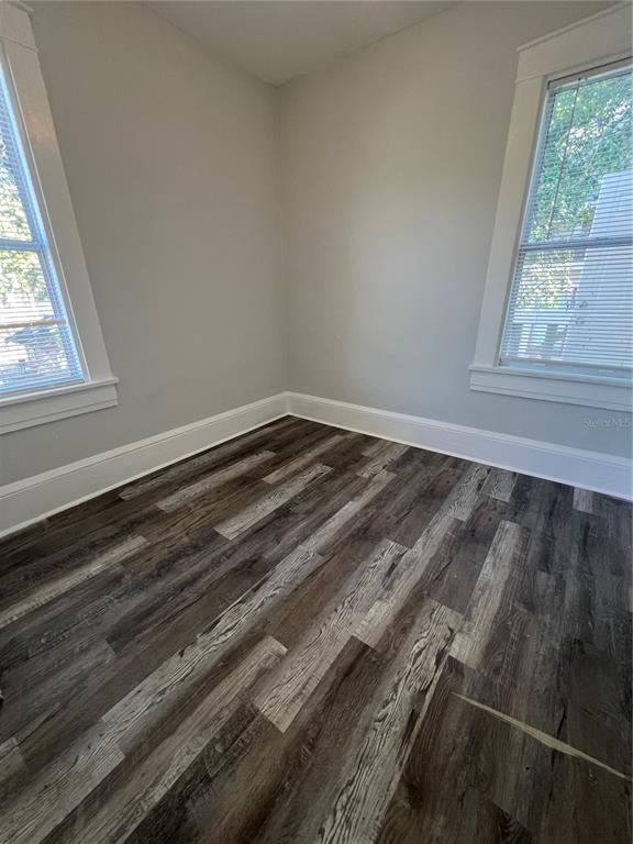 An empty room with light gray walls, white trim, and dark wood-look plank flooring — 209 TAYLOR AVENUE UNIT 2, DAYTONA BEACH, FL
