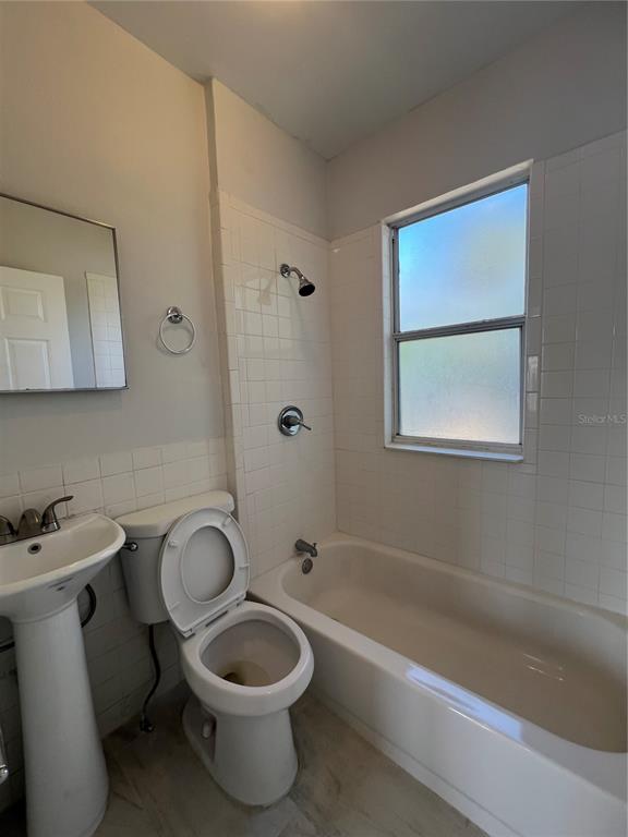 A bathroom features a pedestal sink, a toilet, and a shower-tub combination with white tiles — 209 TAYLOR AVENUE UNIT 2, DAYTONA BEACH, FL