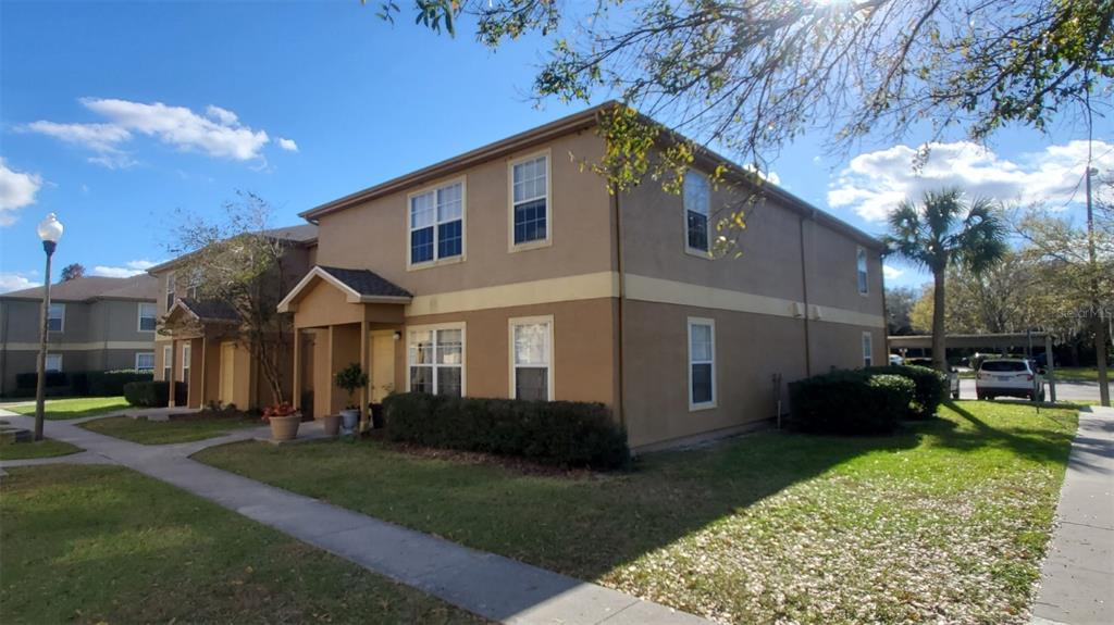A two-story tan apartment building with a covered entryway and a sidewalk in front — 5914 WILLOW RIDGE DRIVE UNIT 101, ZEPHYRHILLS, FL