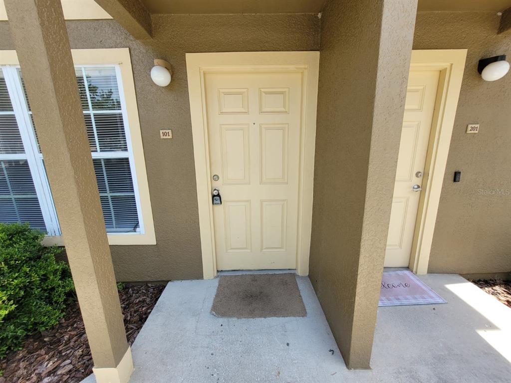 Exterior view of two apartment unit entrances with tan doors and a concrete walkway — 5914 WILLOW RIDGE DRIVE UNIT 101, ZEPHYRHILLS, FL