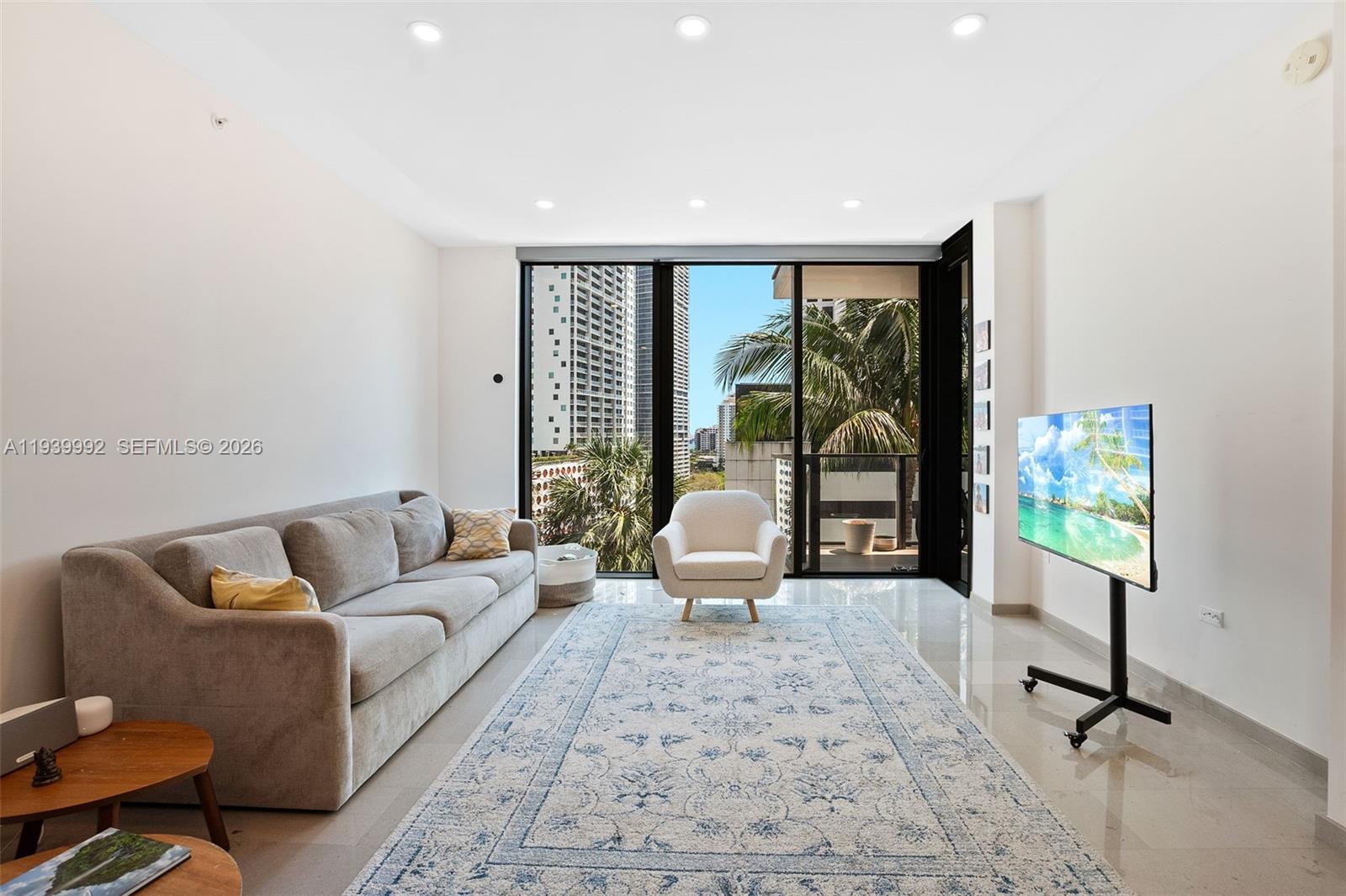 A living room features a grey sofa, an armchair, a rug, and a portable television — 68 SE 6th Street # 805, Miami FL 33131, MIAMI, FL