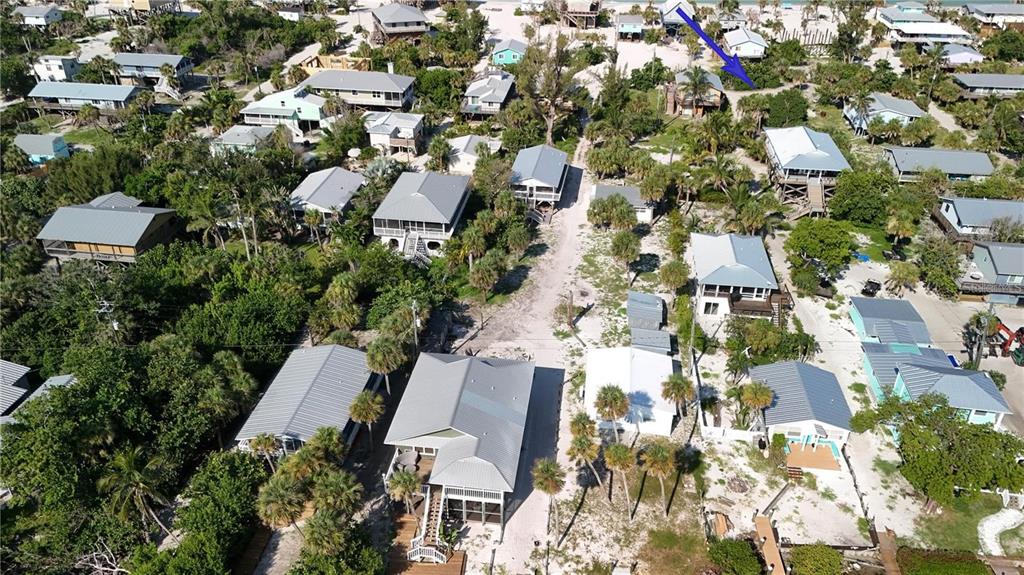 An aerial view shows a coastal neighborhood with numerous houses nestled among trees and sand — 8480 LITTLE GASPARILLA ISLAND, PLACIDA, FL