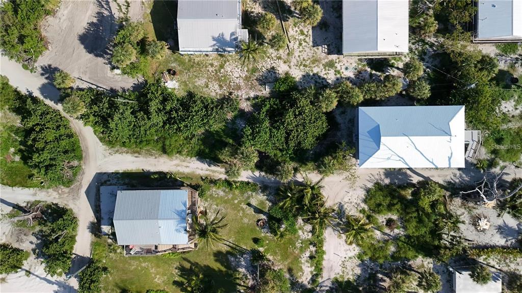 An aerial view shows several houses with metal roofs surrounded by sandy ground and vegetation — 8480 LITTLE GASPARILLA ISLAND, PLACIDA, FL