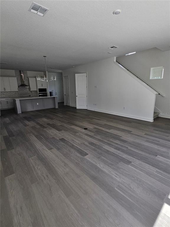 An open-concept living area features gray wood-look flooring, a kitchen island, and a staircase — 10172 PEARSON AVENUE, ORLANDO, FL