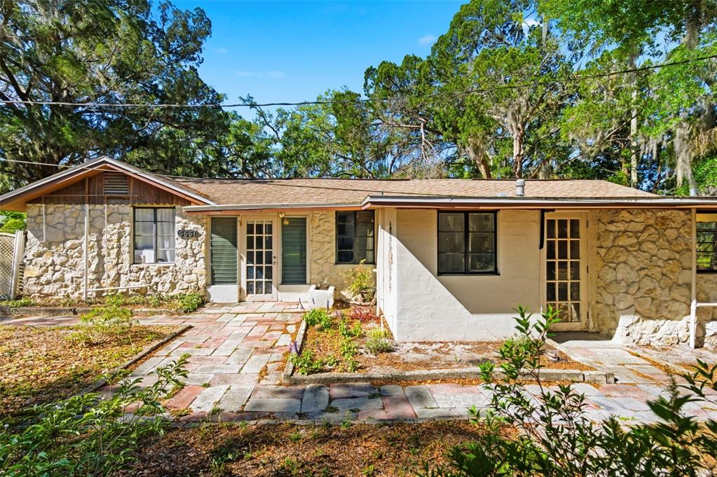 A single-story house with a stone facade, a paved walkway, and mature trees — 5651 MONROE STREET, NEW PORT RICHEY, FL