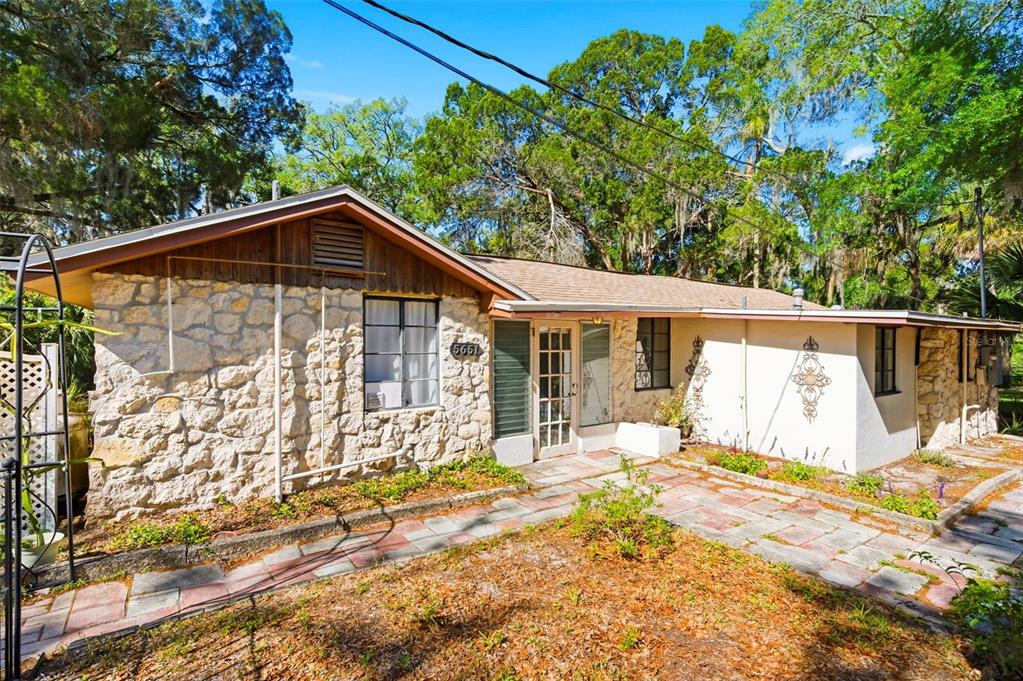 A single-story house features a stone facade, a wood-paneled gable, and a stone-paved walkway — 5651 MONROE STREET, NEW PORT RICHEY, FL