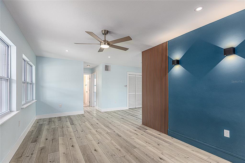 A room with light blue walls, wood-look flooring, a ceiling fan, and a blue accent wall — 3208 PINETREE STREET, PORT CHARLOTTE, FL