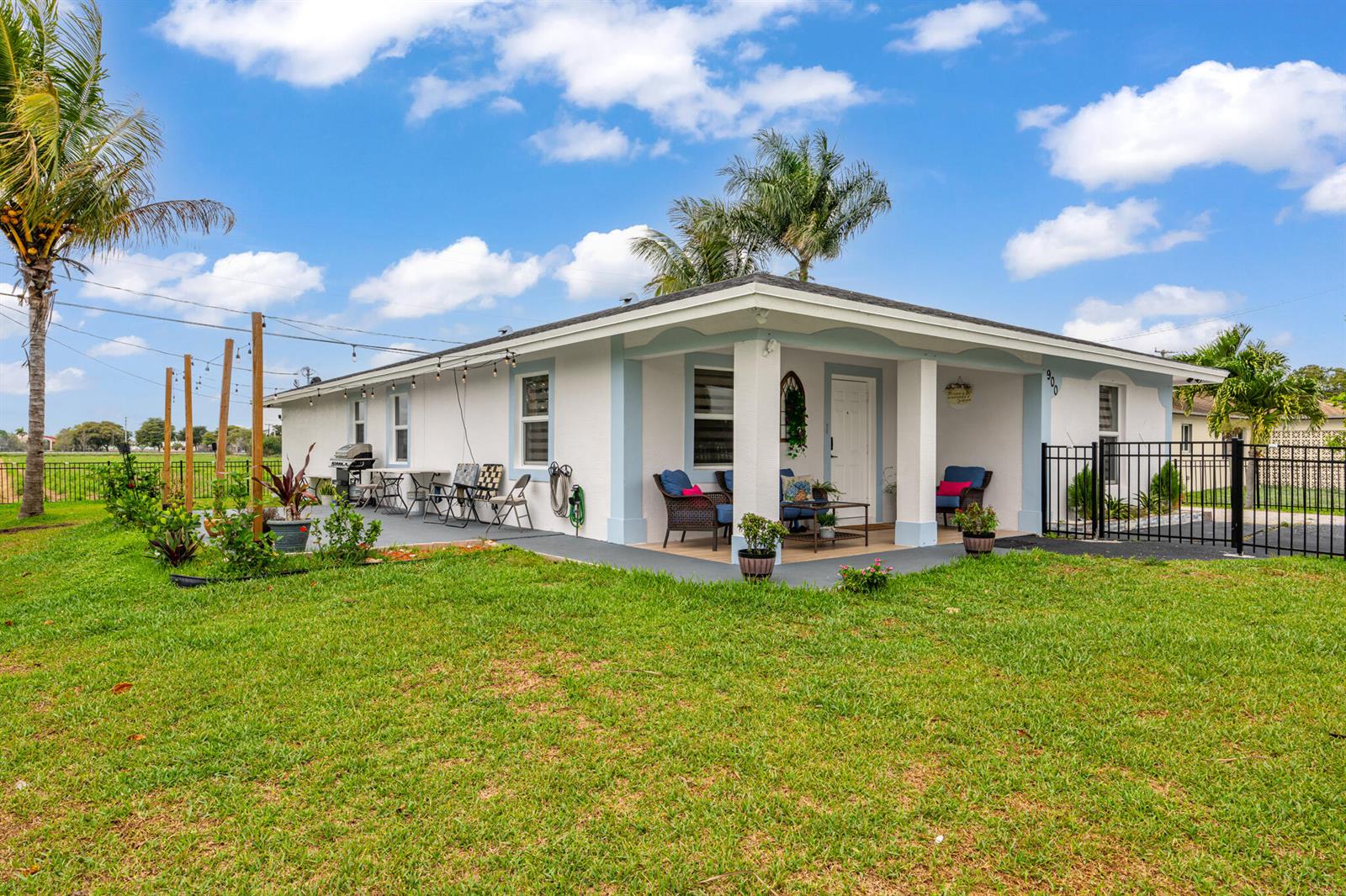 A single-story white house with a covered front porch and a large grassy yard — 900 SW 12th Street, Belle Glade FL 33430, BELLE GLADE, FL