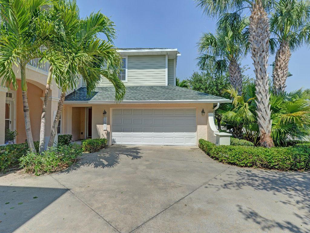 A two-story house with a white garage door, light siding, and palm trees in front — 1645 Baseline Lane, Vero Beach FL 32967, VERO BEACH, FL