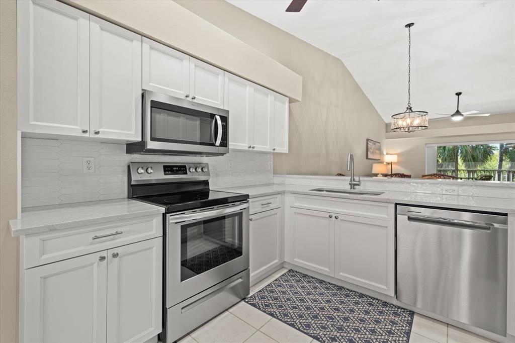 A kitchen features white cabinets, stainless steel appliances, and a patterned rug on tile floors — 9550 HIGH GATE DRIVE UNIT 1525, SARASOTA, FL