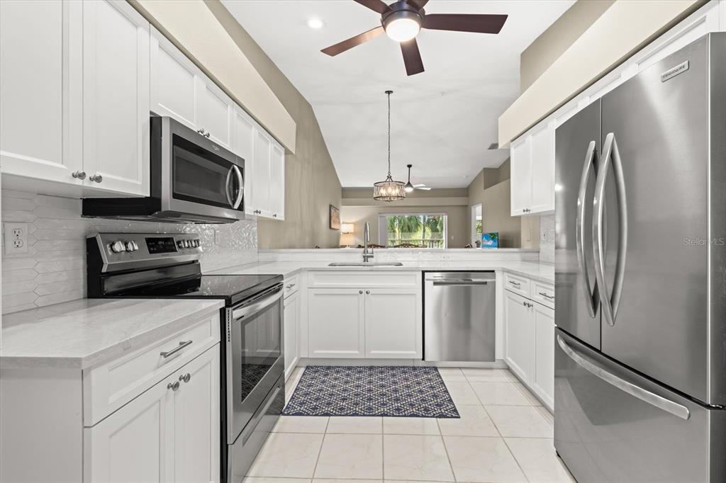 A kitchen with white cabinets, stainless steel appliances, and a tiled floor — 9550 HIGH GATE DRIVE UNIT 1525, SARASOTA, FL