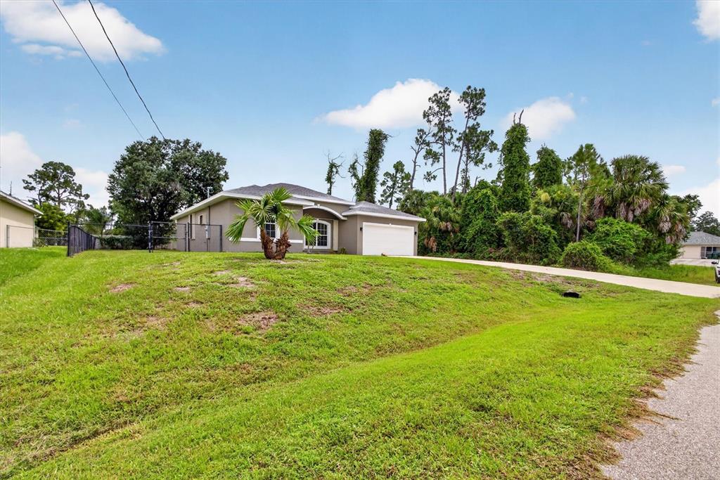 A single-story house with a white garage and a grassy sloped yard — 1146 WOODCREST LANE, NORTH PORT, FL