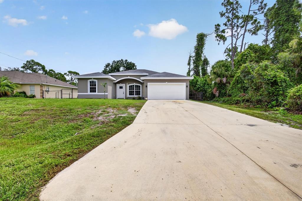 A single-story house with a gray exterior, a white garage door, and a concrete driveway — 1146 WOODCREST LANE, NORTH PORT, FL