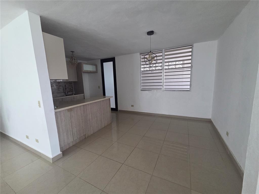 An open-concept kitchen with light wood cabinets and a breakfast bar overlooks a tiled room — 24 calle 35 VILLA CAROLINA, CAROLINA, PR
