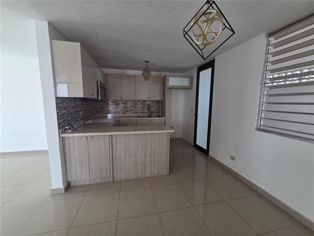 A kitchen with light wood cabinets, a tiled backsplash, and a breakfast bar — 24 calle 35 VILLA CAROLINA, CAROLINA, PR