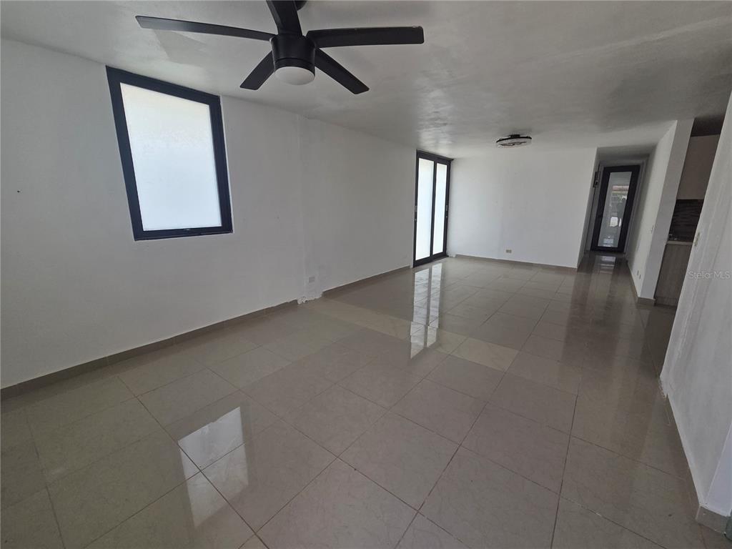 An empty room with white walls, large floor tiles, a ceiling fan, and a doorway — 24 calle 35 VILLA CAROLINA, CAROLINA, PR