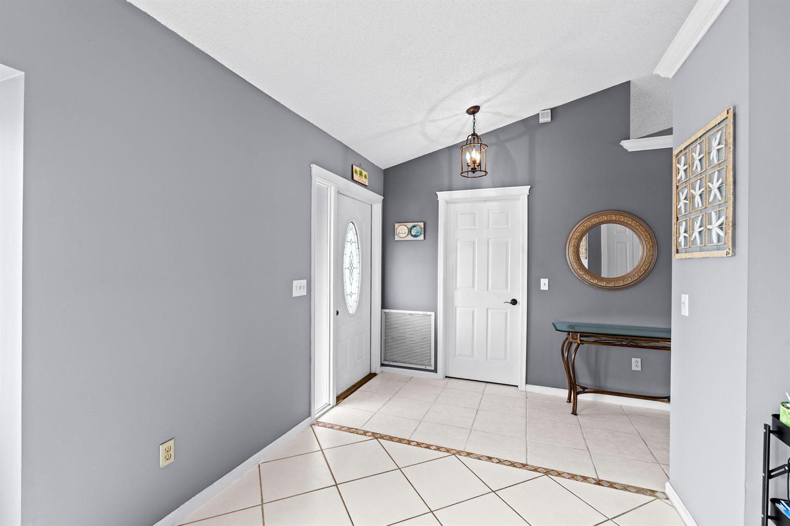 An entryway with gray walls, white trim, tile flooring, a glass console table, and mirror — 986 Cherry Lane, Wellington FL 33414, WELLINGTON, FL
