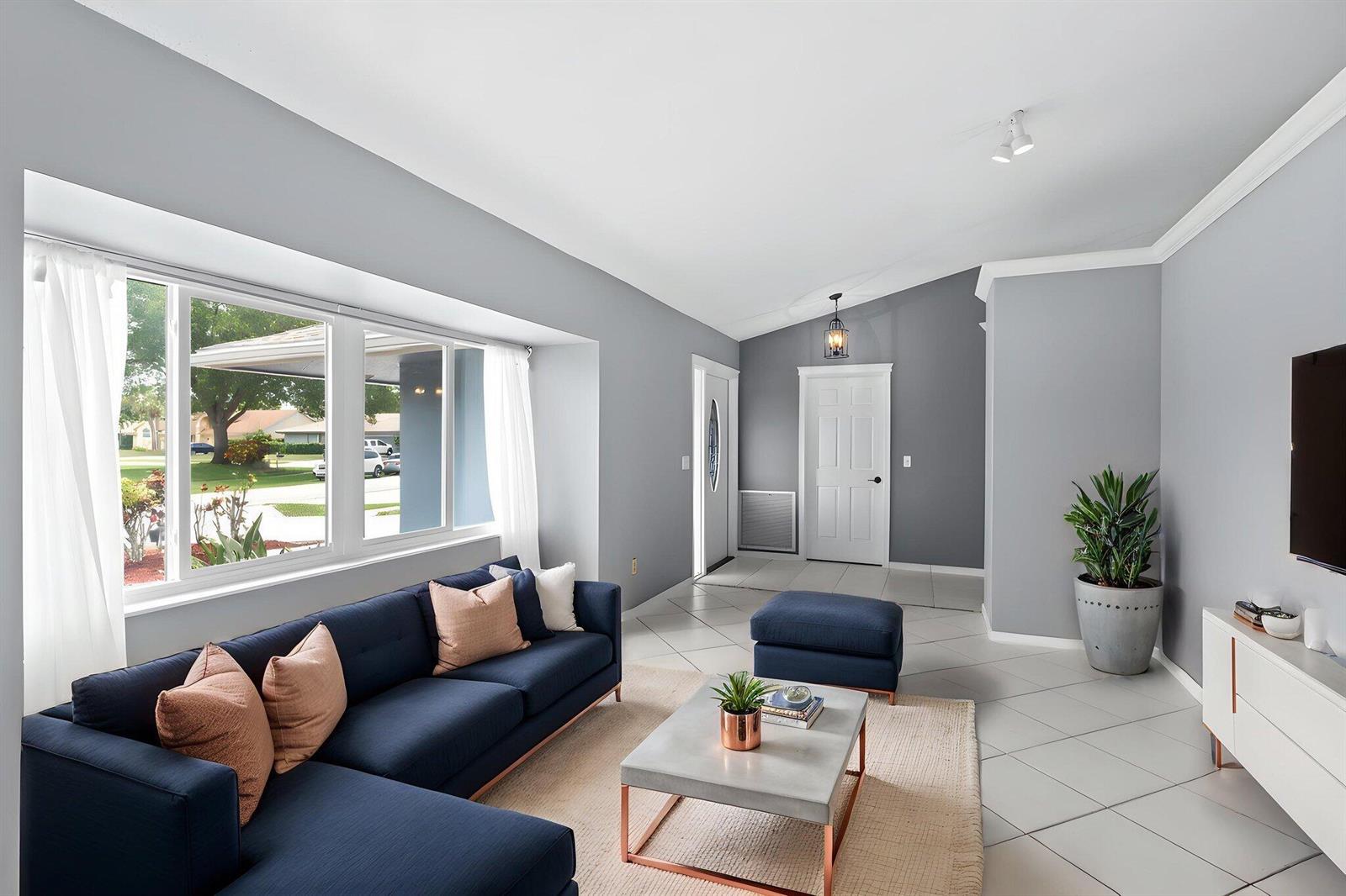 A living room features a blue sectional sofa, a concrete coffee table, and tile flooring — 986 Cherry Lane, Wellington FL 33414, WELLINGTON, FL