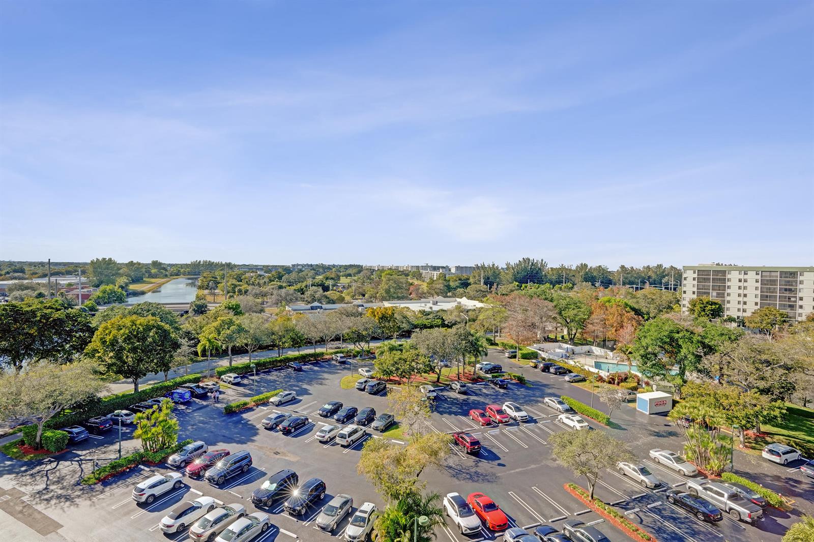 An elevated view shows a parking lot surrounded by trees and a nearby apartment building — 2334 S Cypress Bend Drive # 907, Pompano Beach FL 33069, POMPANO BEACH, FL