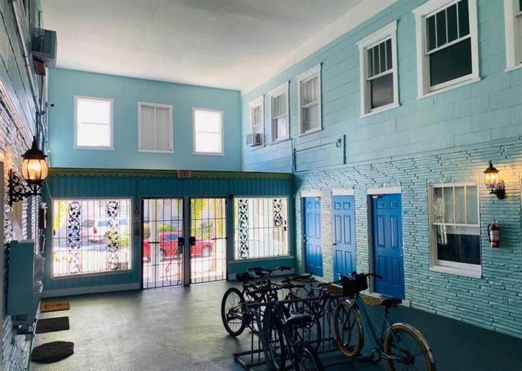 A covered outdoor breezeway features light blue walls, a bike rack, and several blue doors — 308 GROVE STREET N, ST PETERSBURG, FL