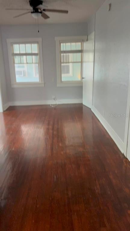An empty room features hardwood floors, light gray walls, and two windows with white trim — 308 GROVE STREET N, ST PETERSBURG, FL