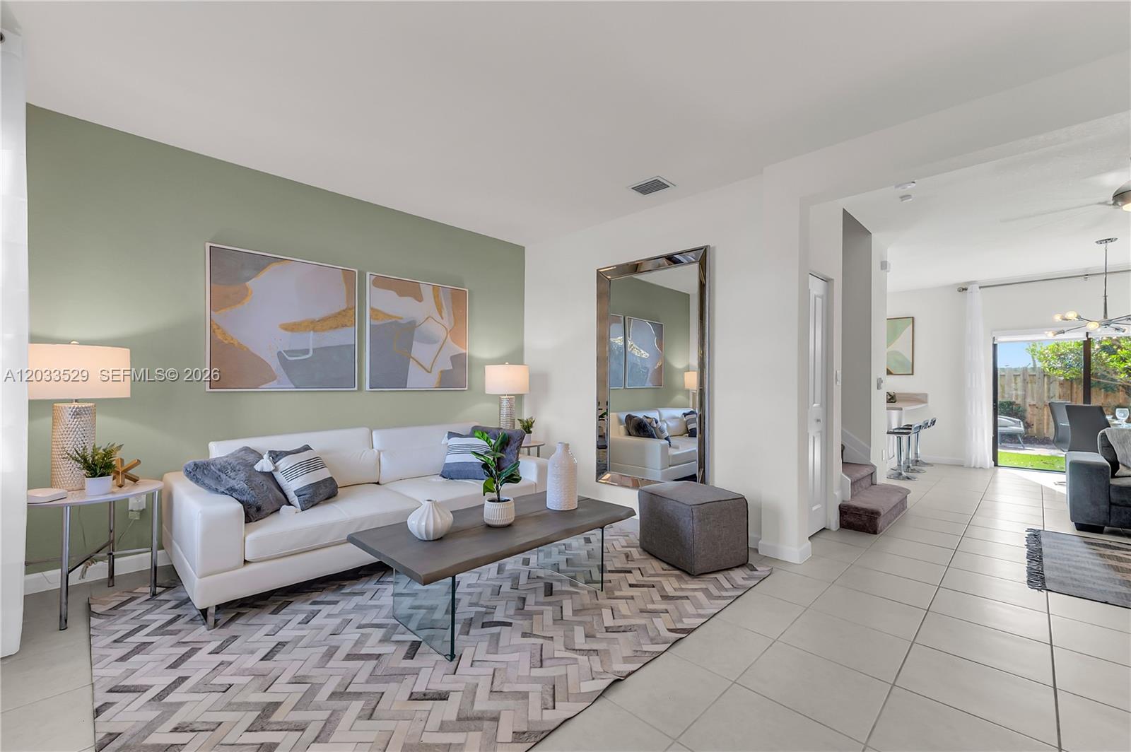 A living room features a white sofa, a patterned rug, and a sage green wall — 12980 SW 233rd Ter, Homestead FL 33032, HOMESTEAD, FL