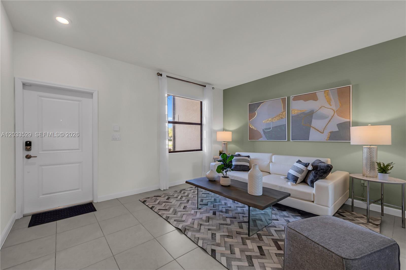 A living room features a white sofa, a coffee table, and a sage green accent wall — 12980 SW 233rd Ter, Homestead FL 33032, HOMESTEAD, FL