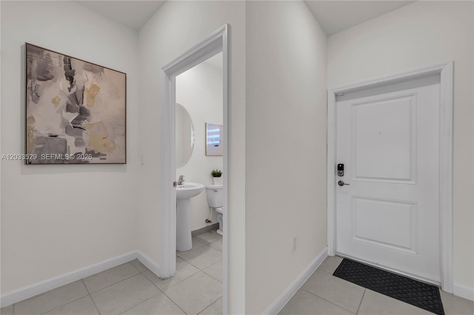 An entryway features a white door, tile flooring, and a doorway leading to a bathroom — 12980 SW 233rd Ter, Homestead FL 33032, HOMESTEAD, FL