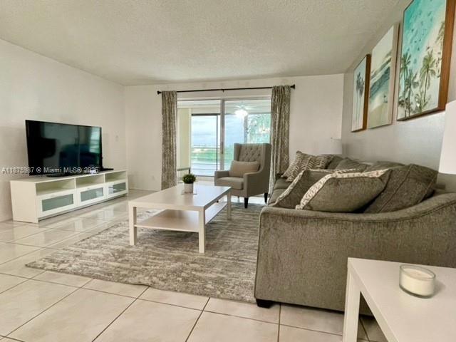 A living room features a television on a white media console, a sofa, and tile floors — 131 SE 3rd Ave # 305, Dania Beach FL 33004, DANIA BEACH, FL
