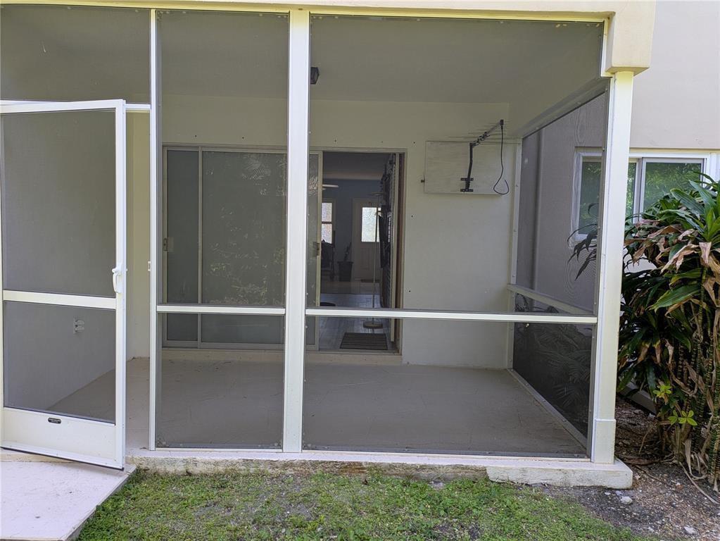 A screened-in patio with a white frame, concrete floor, and a sliding glass door entrance — 2115 NE 42nd Court # 104N, Lighthouse Point FL 33064, LIGHTHOUSE POINT, FL
