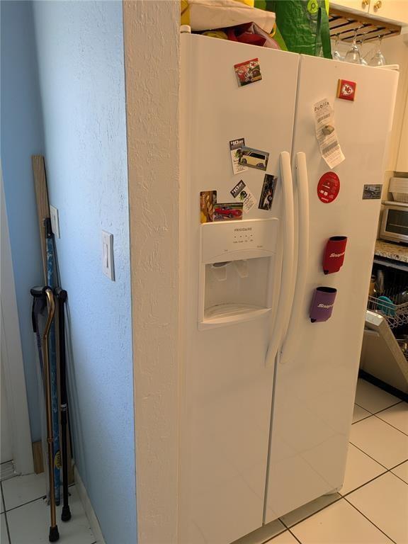 A white side-by-side refrigerator stands in a kitchen next to a wall with walking canes — 2115 NE 42nd Court # 104N, Lighthouse Point FL 33064, LIGHTHOUSE POINT, FL