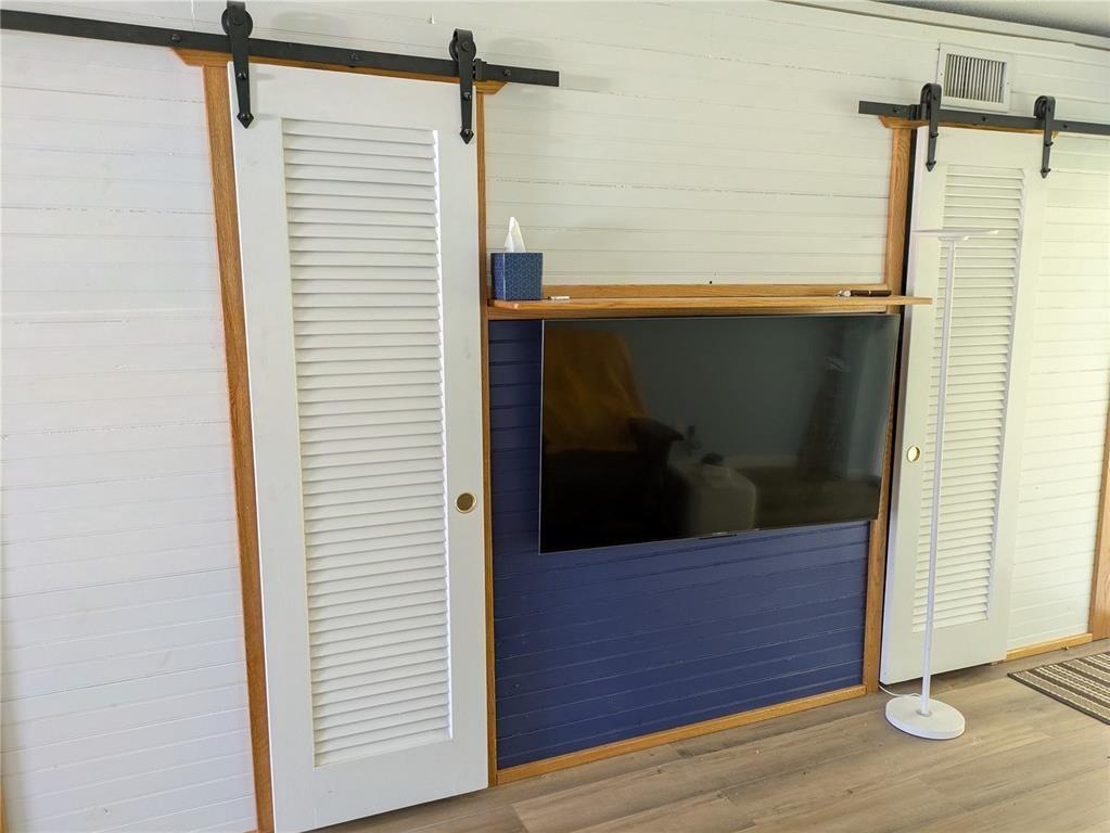 A wall-mounted television sits on a blue shiplap section between two white louvered sliding doors — 2115 NE 42nd Court # 104N, Lighthouse Point FL 33064, LIGHTHOUSE POINT, FL