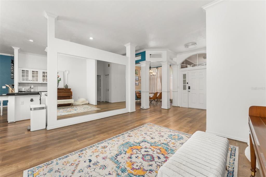 A living room features wood flooring, a large wall mirror, and a white front door — 11520 NW 8TH LANE, GAINESVILLE, FL