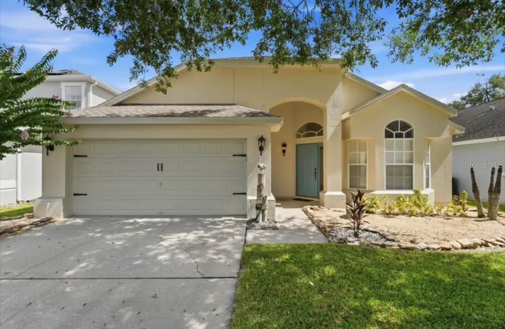 A single-story house with a light-colored stucco exterior, a two-car garage, and a blue front door — 2782 JOSEPH CIRCLE, OVIEDO, FL
