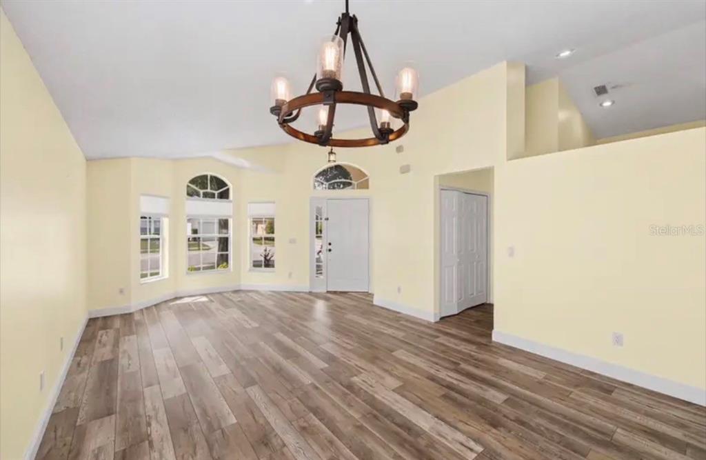 An empty room with light yellow walls, wood-look flooring, and a large rustic chandelier — 2782 JOSEPH CIRCLE, OVIEDO, FL