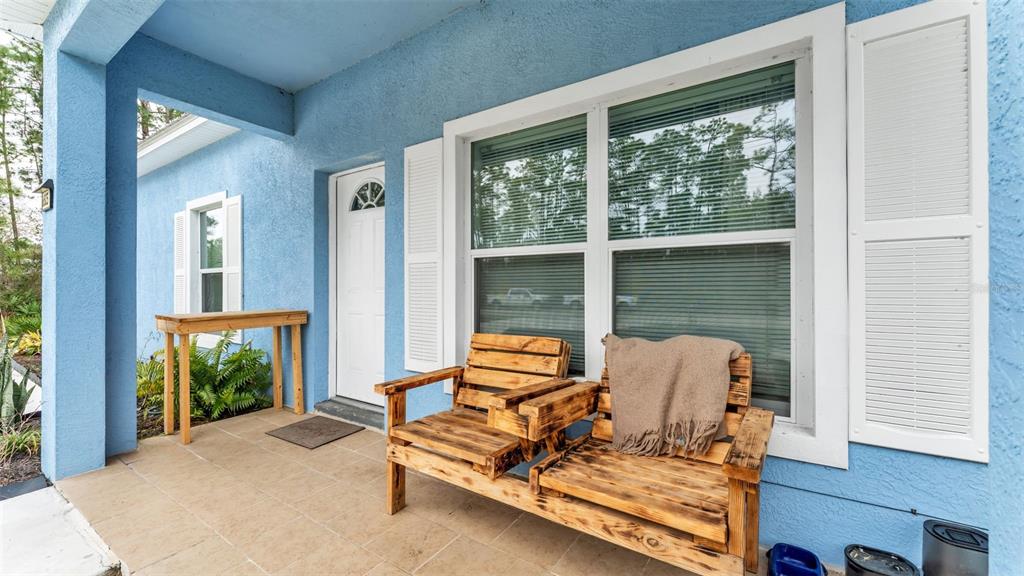 A blue house exterior features a covered porch with a wooden bench and a table — 6503 BURKETT AVENUE, SEBRING, FL