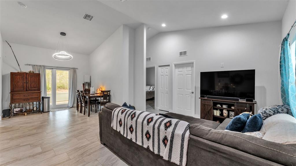 A living room with a sectional sofa, dining area, and television on a wooden stand — 6503 BURKETT AVENUE, SEBRING, FL