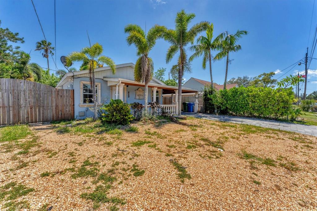 A light blue house with a gravel front yard, palm trees, and a wooden fence — 513 25TH AVENUE W, BRADENTON, FL