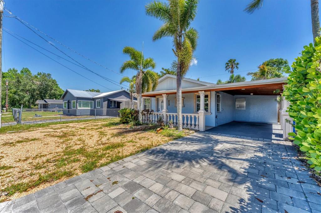 A light blue house with a paved driveway, a carport, and palm trees in the yard — 513 25TH AVENUE W, BRADENTON, FL