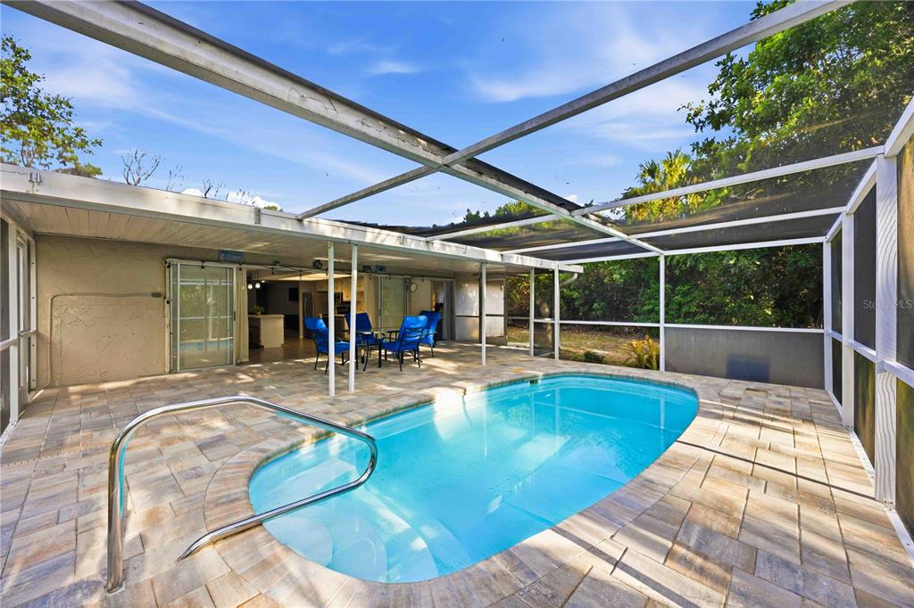 A screened-in patio features a swimming pool with a metal handrail and stone pavers — 2091 CANNOLOT BOULEVARD, PORT CHARLOTTE, FL