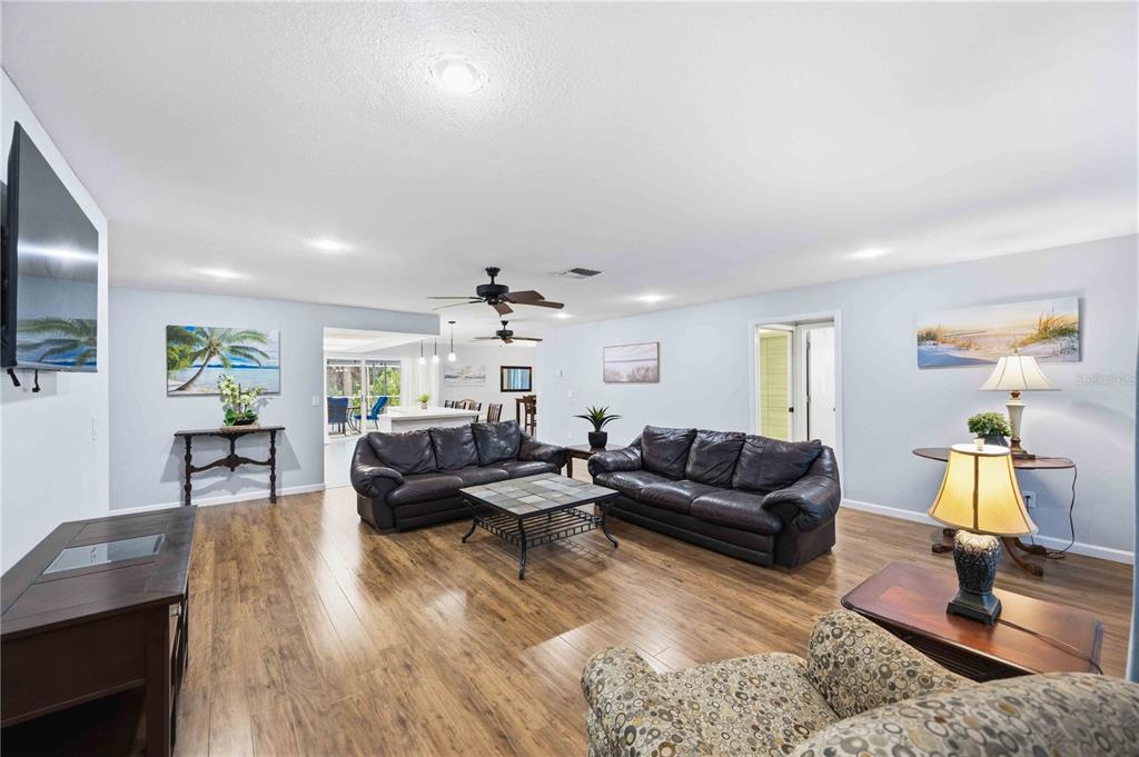 A spacious living room features dark leather sofas, wood-look flooring, and recessed ceiling lighting — 2091 CANNOLOT BOULEVARD, PORT CHARLOTTE, FL