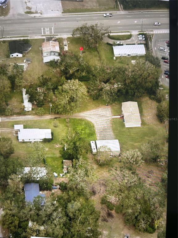 An aerial view shows several residential buildings, a gravel driveway, and trees on a lot — 7707 GIBSONTON DRIVE, GIBSONTON, FL