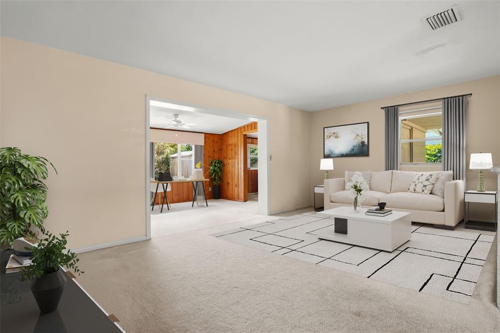 A living room with beige carpet, a white sofa, and a doorway leading to a sunroom — 5409 STRATEMEYER DRIVE, ORLANDO, FL